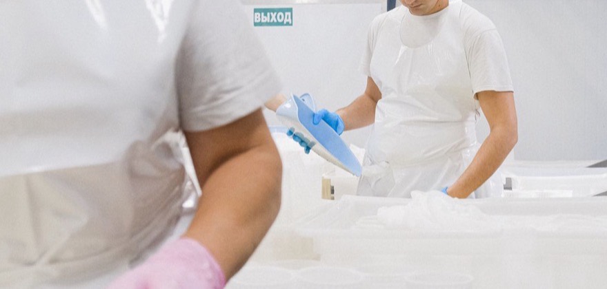Workers in protective gear processing product in a dairy factory