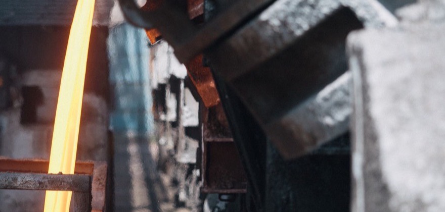 Molten metal pouring from a ladle on a steel melt shop floor